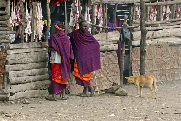 Maasai men buying meat at primitive butcher's shop in village
