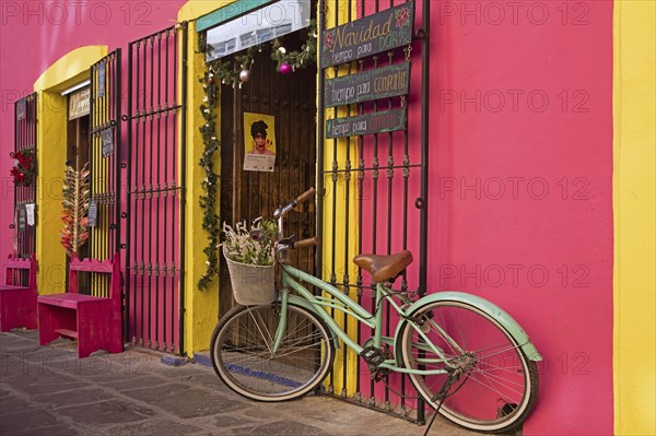 Colourful pink and yellow storefront with decorative bicycle in the city Puebla