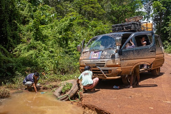 Cleaning radiator of minibus in the rain forest along the Linden-Lethem track