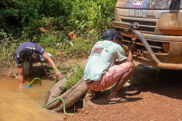 Cleaning radiator of minibus in the rain forest along the Linden-Lethem track