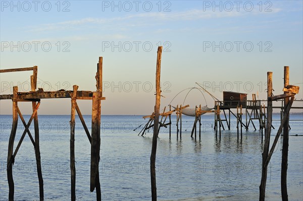 Remains of wooden walkway of traditional carrelet fishing hut on the beach at sunrise