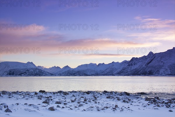 View over the Gimsoystraumen fjord and mountains in the snow in winter at sunrise