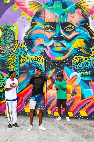 Breakdancing in front of graffiti on the wall of a house