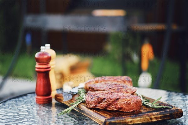 Closeup view of beefsteak on glass table on backyard