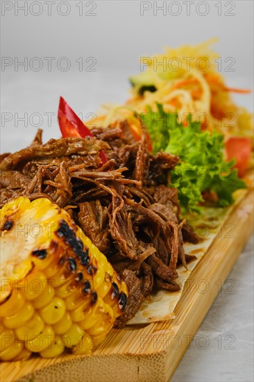 Pulled beef served with grilled corn and pickled cabbage