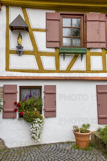 Detail of a half-timbered house on the Rottenburg quay with two windows and a small religious figure on the facade