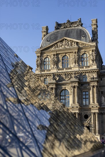 Detail of the Louvre Museum building with reflection on the glass pyramid