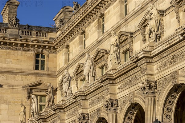 Detail of the opulent Louvre Museum building with sculptures on top