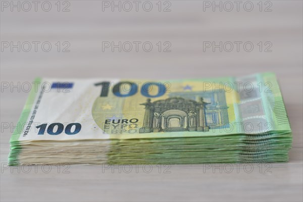Many one hundred euro notes in a pile on a table