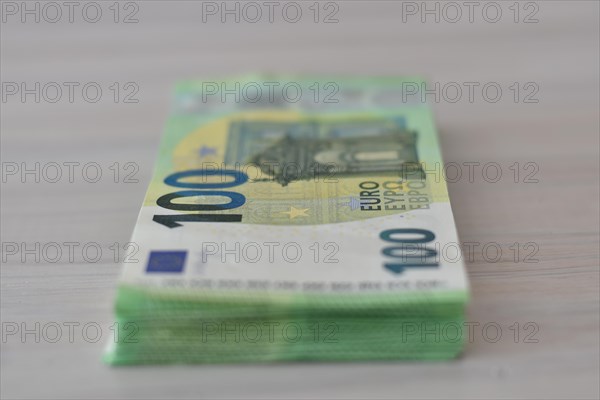 Many one hundred euro notes in a pile on a table