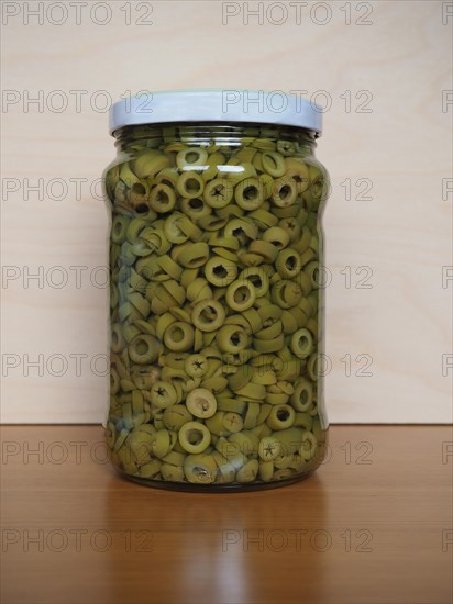 Sliced green olives in brine in glass jar