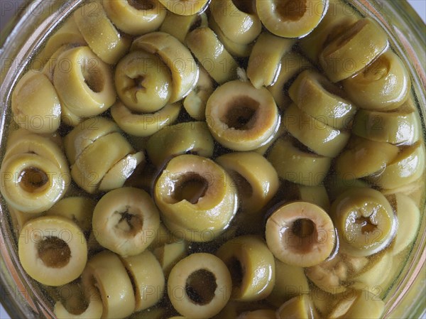 Sliced green olives in brine background