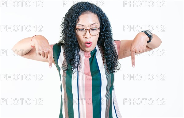 Surprised afro young woman pointing at advertising down isolated. Shocked latin woman pointing and looking down