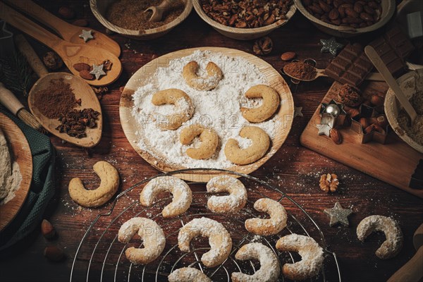 Baked vanilla crescents on a cake rack and in icing sugar