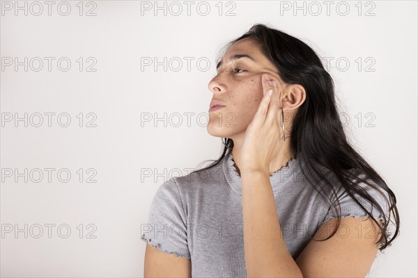 Beauty face. Black haired latin woman touching healthy skin on white background