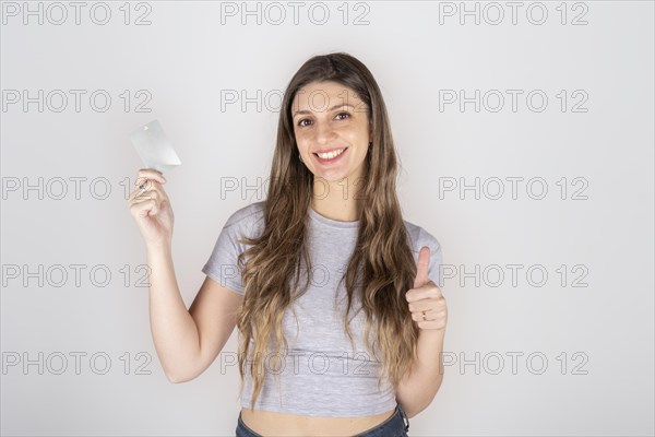 Smiling young blond latin american woman 20s in gray casual clothes isolated on white background studio portrait. People sincere emotions lifestyle concept. Copy space. Hold credit bank card