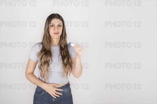 Portrait of a young blond woman holding pregnancy test feeling shocked