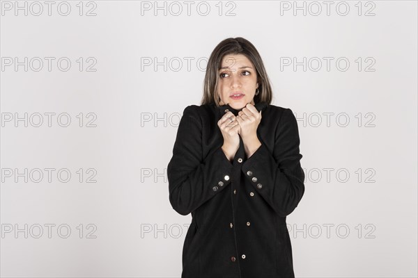 Studio portrait of young blonde woman wearing a black coat with expression of cold and disgust