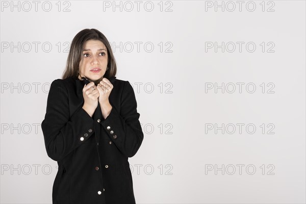 Studio portrait of young blonde woman wearing a black coat with expression of cold and disgust