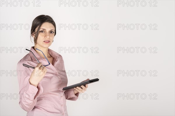 Studio portrait of a young blonde business woman holding a tablet and glasses. White background. Copy space