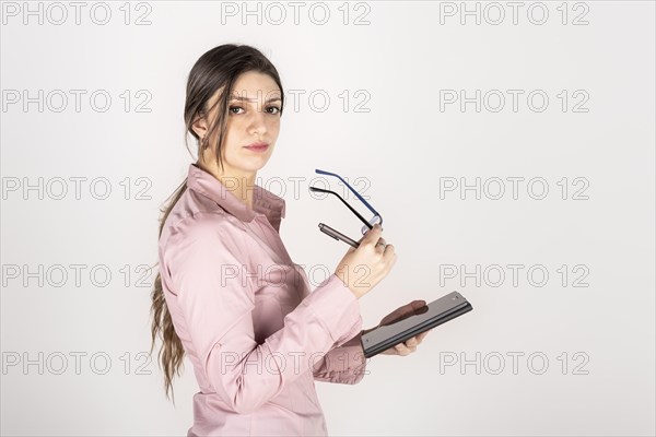 Studio portrait of a young blonde business woman holding a tablet and glasses. White background. Copy space