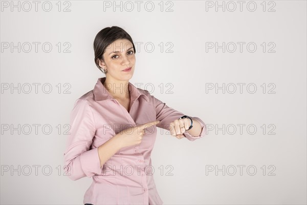 Young beautiful latin american blond business woman standing over white background in hurry pointing to watch time