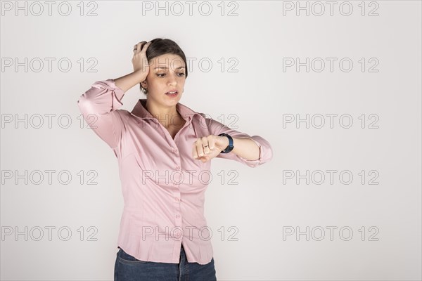 Young beautiful latin american blond business woman standing over white background in hurry looking to watch time