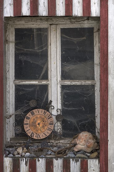 Window of an old farmhouse with cobwebs and old kitchen clock