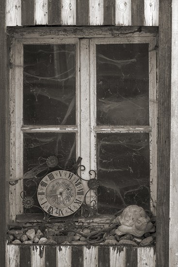 Window of an old farmhouse with cobwebs and old kitchen clock