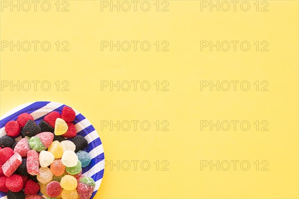 Jelly candies striped plate yellow background