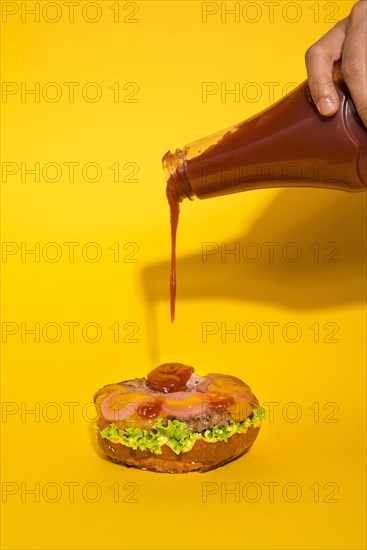 Ketchup pouring tasty burger bun