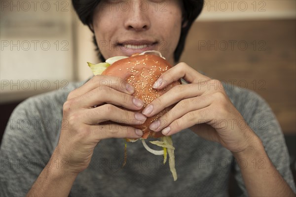 Male eating hamburger cafe