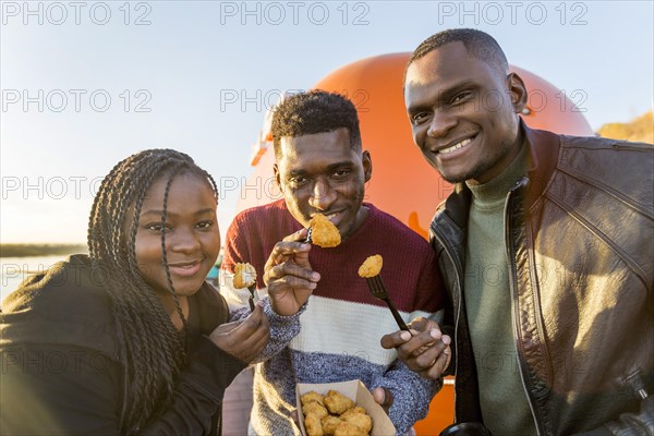 Mid shot people eating chicken nuggets out takeout packaging