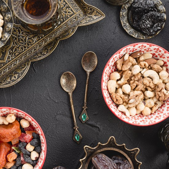 Mixed nuts tea dried fruits metallic spoons black concrete backdrop