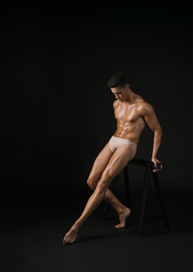 Muscular dancer leaning barre