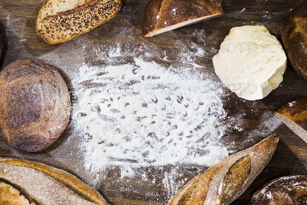 Overhead view loaf bread baguette kneaded dough with flour wooden desk