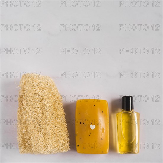 Overhead view natural loofah herbal soap essential oil bottle against white background