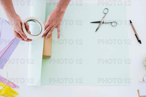 Overhead view woman s hand sticking paper gift box white desk