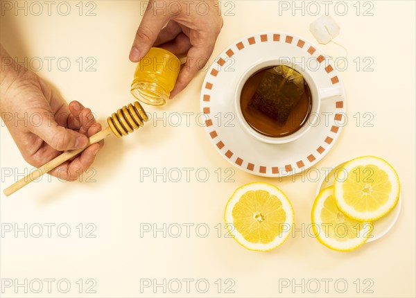 Person s hand peaking honey from jar healthy tea