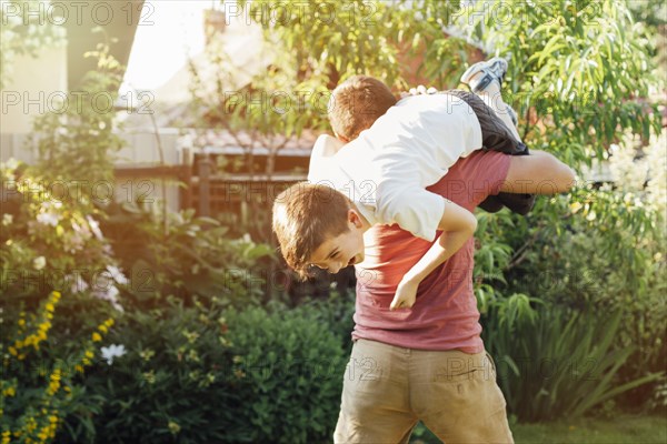 Playful father carrying his smiling son shoulder park
