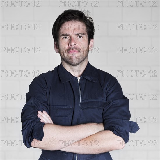 Portrait confident male electrician standing against wall