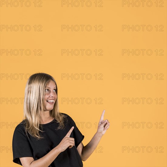 Portrait happy woman pointing upward direction looking up