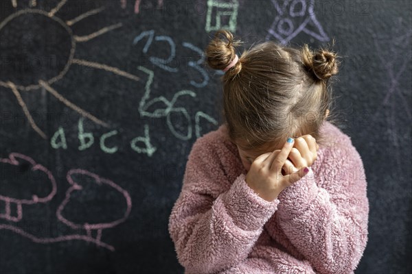 Portrait little girl upset covering her face