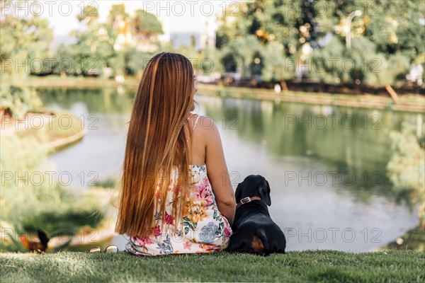 Rear view woman dachshund sitting near pond