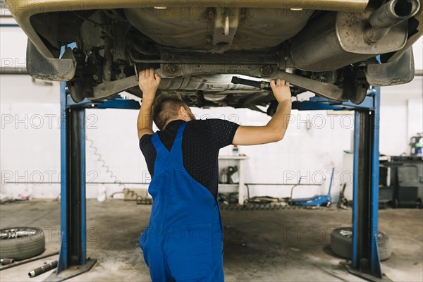 Repairmen examining car bottom