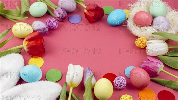 Round frame from easter eggs tulips red table