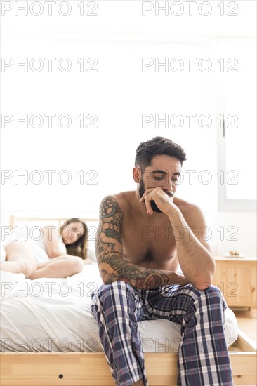 Sad young man sitting bed front his girlfriend