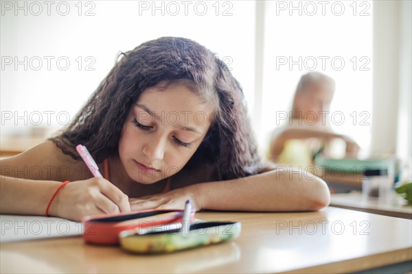 Schoolgirl sitting desk writing