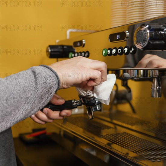Side view male barista cleaning professional coffee machine