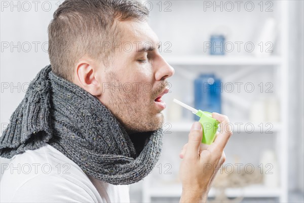 Side view man squirting throat with spray